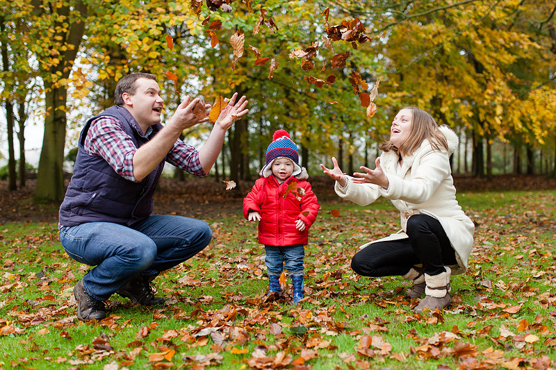 A family have fun throwing autumn leaves during their family photoshoot
