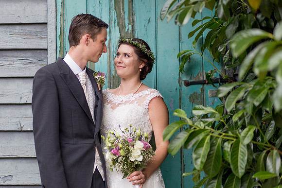 A Bride and Groom in front of a rustic turquoise barn following their wedding