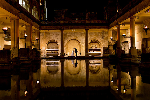 A Bride and Groom are silhouetted in the Roman Baths after their wedding ceremony