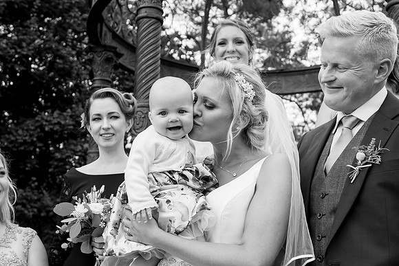 A bride kisses a smiling baby following her wedding