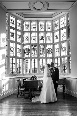 A Bride and Groom in front of the stained glass window at Elmore Court wedding venue