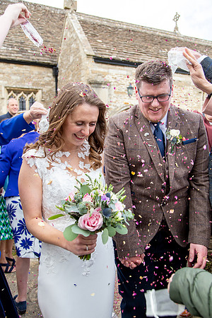 A Bride and Groom are showered with confetti after their church wedding